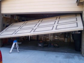 broken garage door that has come off of it's tracks